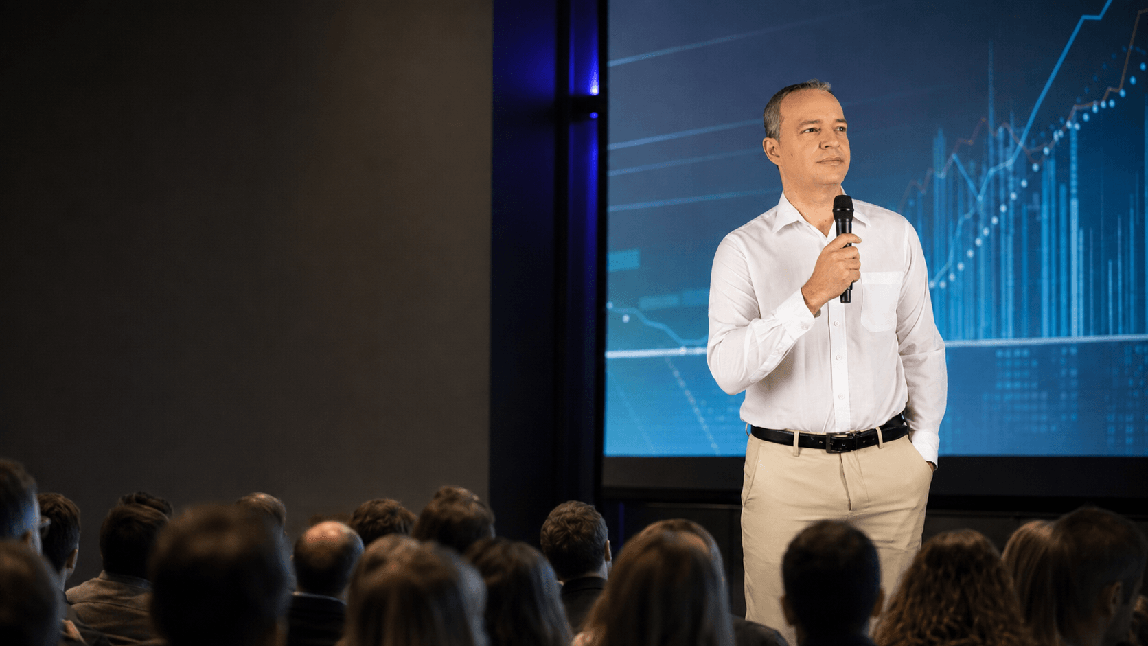 Paulo Crispim palestrando com microfone diante de uma plateia corporativa